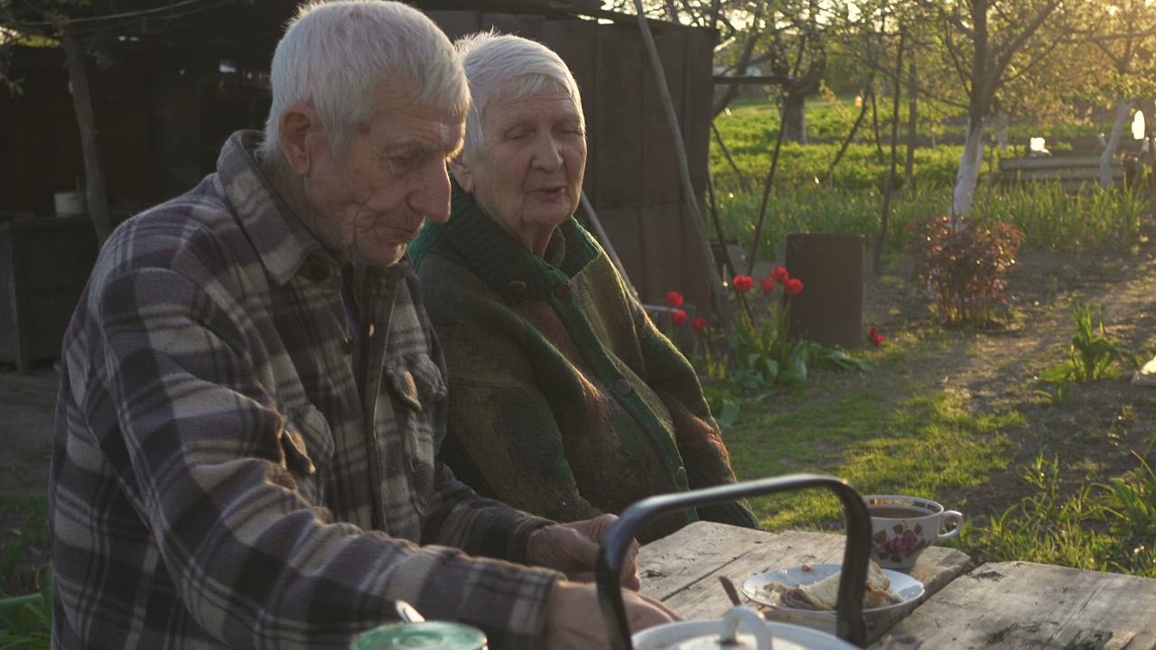 An older couple sitting together in a sunny garden